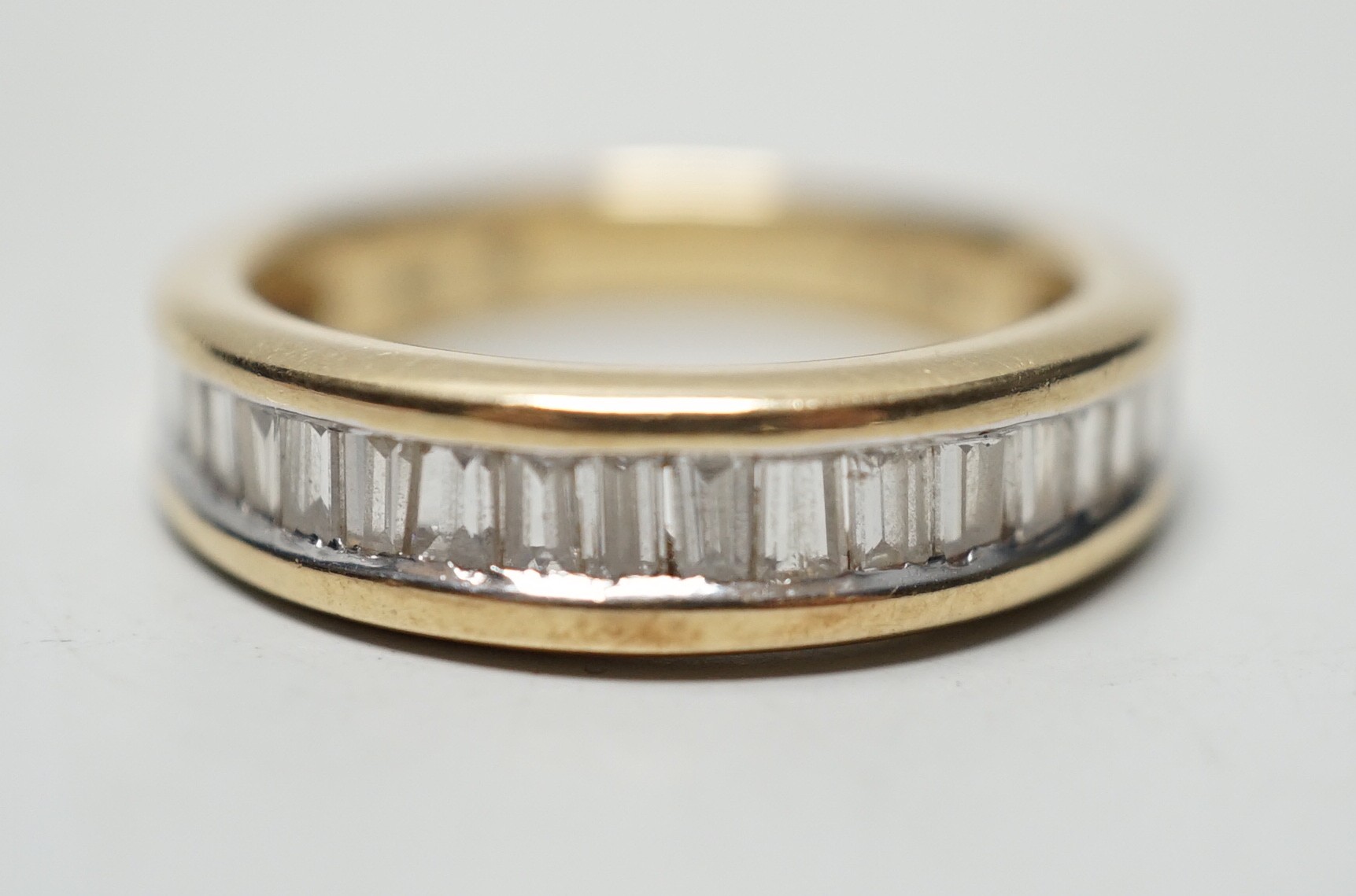 A modern 14k yellow metal and graduated baguette and trapeze cut diamond set half eternity ring, size N, gross weight 4.6 grams.